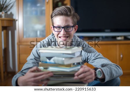 Teenager sitting in front of books  and smiling to the camera.