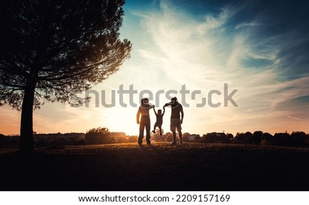 Silhouette of happy family walking in the meadow at sunset - Mother, father and child son having fun outdoors enjoying time together - Family, love, mental health and happy lifestyle concept