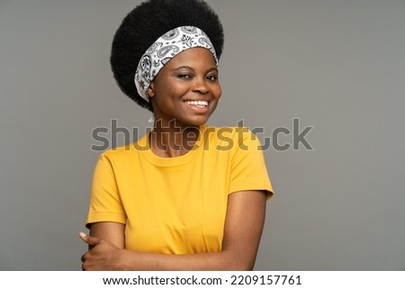 Black female wearing headband on kinky hair enjoys performing on small sketch and showing positive emotions against grey studio wall. Young African American woman wants to become actress in main cast