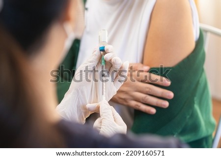 Covid-19,coronavirus, elderly asian adult woman getting vaccine from doctor or nurse giving shot to mature patient at clinic. Healthcare, immunization, disease prevention against flu or virus pandemic Royalty-Free Stock Photo #2209160571