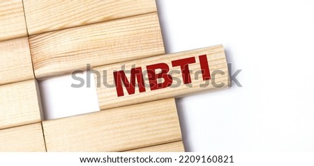 On a light background, wooden blocks with the text MBTI. Close-up top view.