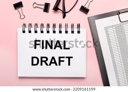 On a pink background, reports, black paper clips, glasses and a white notebook with the text FINAL DRAFT