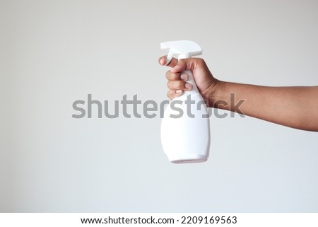 holding a white color disinfectant spray bottle against white wall  Royalty-Free Stock Photo #2209169563