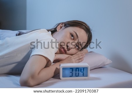 woman have insomnia on the bed selective focus on alarm clock at three in the morning. Royalty-Free Stock Photo #2209170387