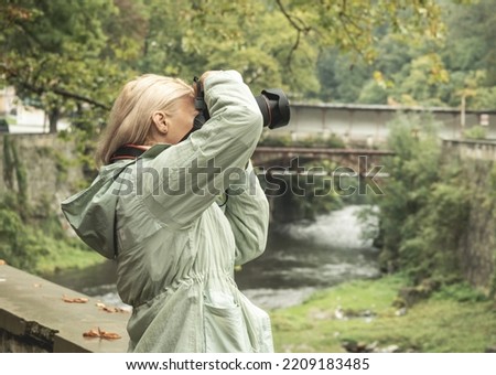Passion for photography. A professional female photographer takes photos on an autumn day.