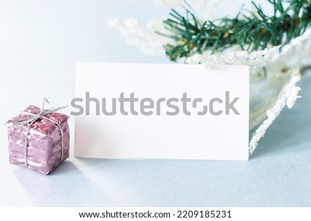 blank text card next to spruce branches and packed gift, festive background