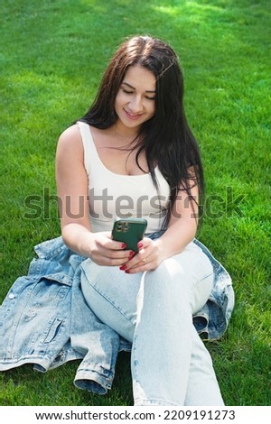 Beautiful young woman outdoor portrait, young woman resting in city park and viewing on her social networks