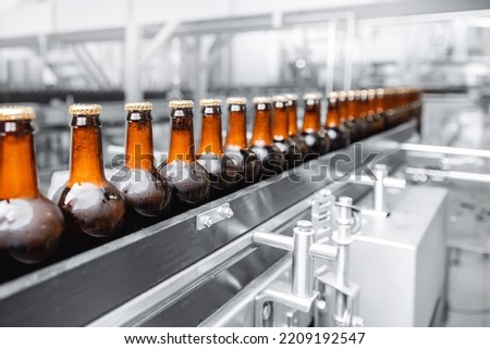 Glass bottles of beer on dark background. Concept banner brewery plant production line. Royalty-Free Stock Photo #2209192547