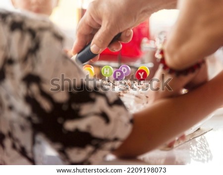 selective focus, cut birthday cake with letter colored inserts meaning a happy birthday. background is a blurry festive table.