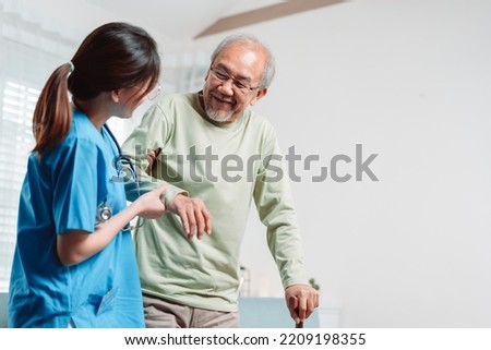 Asian senior elderly man patient doing physical therapy with caregiver. woman nurse helping get up from wheelchair for practice walking with walker at home, practice walk slowly at nursing home care. Royalty-Free Stock Photo #2209198355