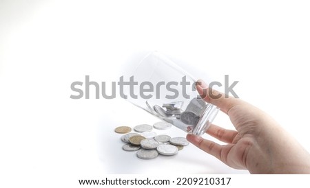 Pouring coins out of a glass isolated on white