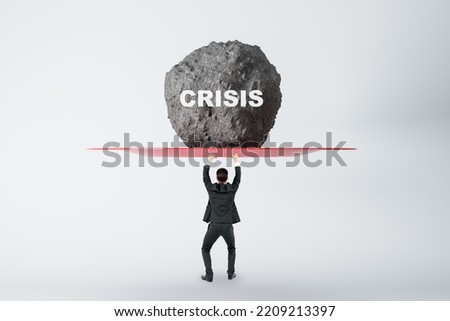 Anti-crisis management concept with businessman back view prevents huge stone from falling on his head with crisis sign on light background