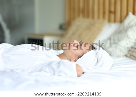 Happy woman resting lying on the bed after showering at home Royalty-Free Stock Photo #2209214105