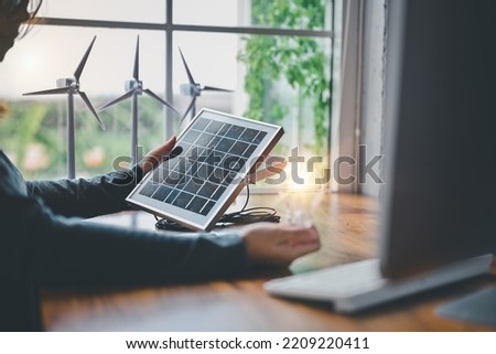 Engineers testing efficiency of solar cell panels type with Led light in office. Learn design and calculation to energy accumulation, use pure energy nature, solar and wind to output Royalty-Free Stock Photo #2209220411