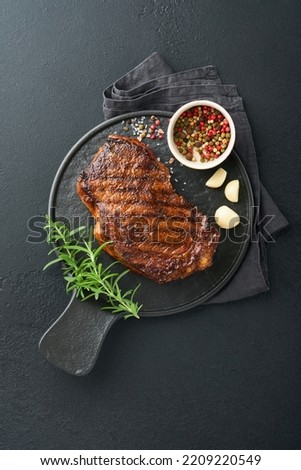Steaks. Grilled New York Steak with spices rosemary and pepper on black marble board on gray background. Top view. Mock up. Royalty-Free Stock Photo #2209220549