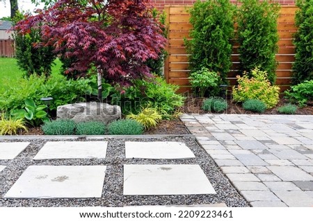 Detail of a beautiful, modern Asian inspired Japanese garden with tumbled paver patio, flagstone walkway and horizontal cedar fence in an urban backyard.	 Royalty-Free Stock Photo #2209223461