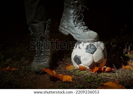 Soccer ball and army boots. A soccer ball on a dark bon.