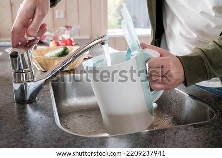 Filling with water electric kettle in the sink from the faucet