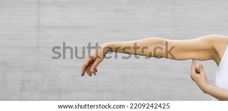 A woman shows the flabby muscles of the arm . Flabby Arm Syndrome (FAS). Effect of aging caused by loss of elasticity and muscle.Banner, copyspace. Royalty-Free Stock Photo #2209242425