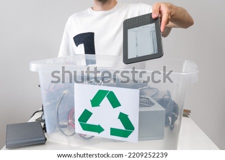 Man throwing away broken electronic book in recycle container. Hazardous E-Waste Recycling. Waste Electrical and Electronic Equipment. Royalty-Free Stock Photo #2209252239