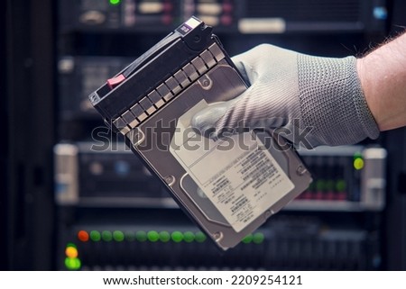 A hard disk for a raid in the hands of a man at a data storage server, close-up Royalty-Free Stock Photo #2209254121