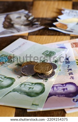 Chinese yuan money and US dollars against the background of chess. Dollar bills and yuan coins from China on a chessboard
