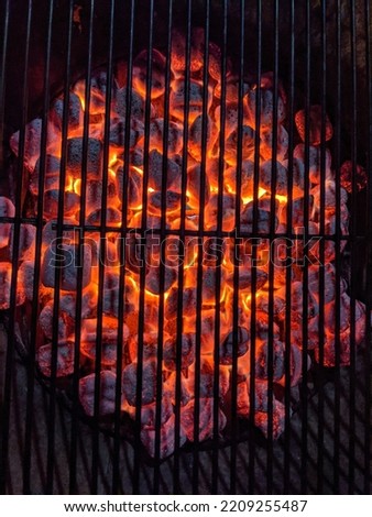 Red Hot Charcoal Coals burning bright orange inside Grill at Night.