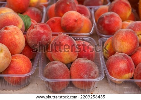 Ripe peaches are in trays on the table. Fresh harvest.