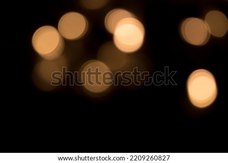 Golden bokeh light isolated on black background, photographic effect. Beautiful Overlay light spots texture, defocused. Holiday Template for design card to New Year, Christmas, Diwali, anniversary