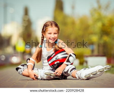 Little girl in roller skates sitting on a city street