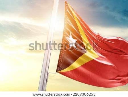 East Timor national flag cloth fabric waving on the sky with beautiful sunlight - Image