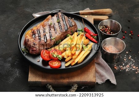 Striploin beef steak with french fries on dark background. Freshly grilled. Healthy dinner. Mediterranean Diet.  Royalty-Free Stock Photo #2209313925