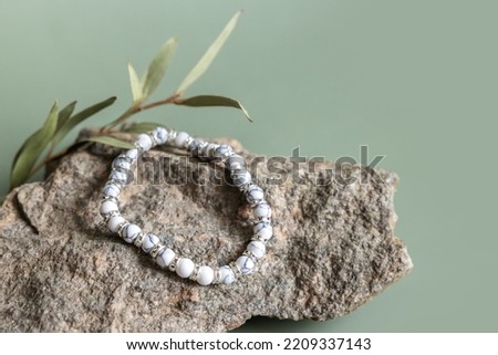 Bracelet made of natural stones beads on pastel green background. Handmade jewelry. Woman exoteric accessories. Talismans and amulets. Selective focus