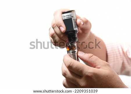 Recharging electronic cigarette. Hands pouring liquid into the vaping machine