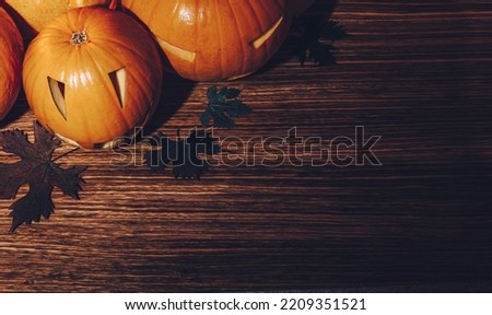 Beautiful Stylish Halloween Still Life on Wooden Background. Carved Jack-o-lanterns Decoration with Dry Maple Leaves. Happy Halloween Party.