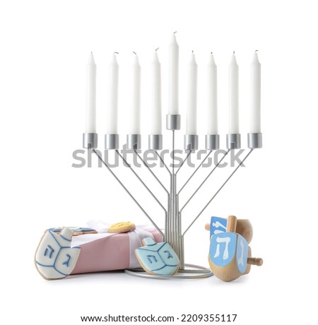 Menorah with candles, dreidels, cookies and gift box for Hanukkah celebration on white background