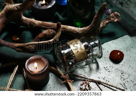 Jar with frog bones and burning candle on dark wizard table