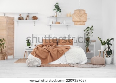 Interior of light bedroom with houseplants and shelves