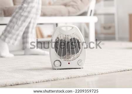 Electric fan heater on carpet in living room Royalty-Free Stock Photo #2209359725
