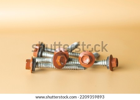 Tapping screws made of steel on orange background, metal screw, iron screw, chrome screw, screws as a background, wood screw, concept industry. High quality picture. Copy space for text.