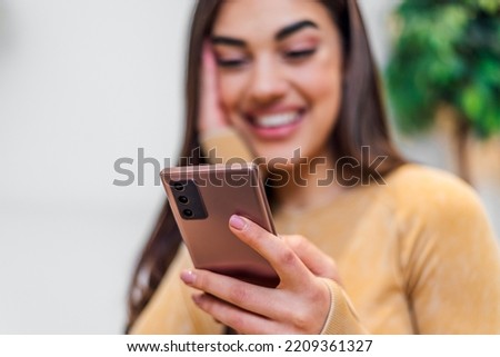 Picture of a young brunette woman, using her new mobile phone, reading messages.