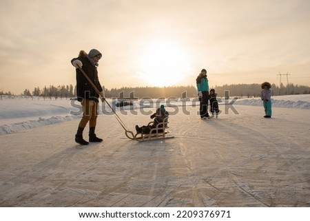 Happy family with three children having fun at ice-skating rink outdoor