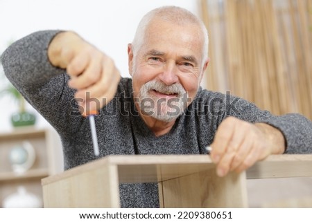 happy senior man with screw and furniture