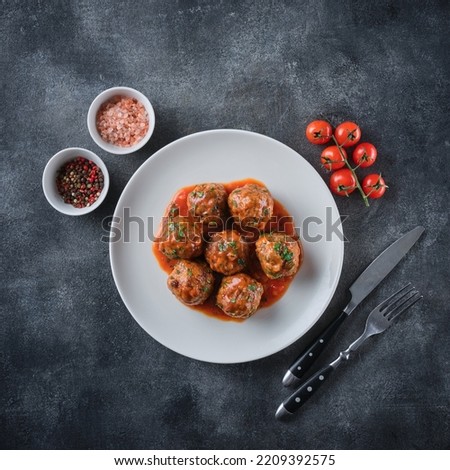 Homemade meatballs with tomato sauce and spices served in plate on grey background. View from above Royalty-Free Stock Photo #2209392575