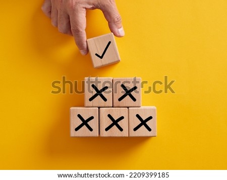 Hand putting wooden cube with tick checkmark right icon over the cross wrong icons. Finding the correct way after making many mistakes. Royalty-Free Stock Photo #2209399185