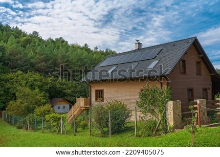 Wooden house with installed solar panels. Alternative energy, saving resources and sustainable lifestyle concept. Royalty-Free Stock Photo #2209405075