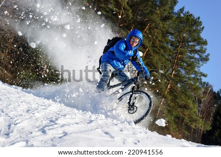 Rider cycling on a mountain bicycle in the snow in the winter forest