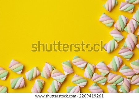 Delicious colorful marshmallows on yellow background, flat lay. Space for text