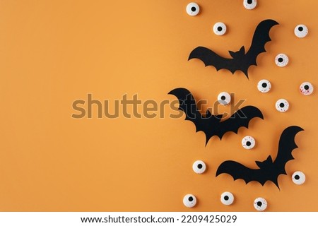 Kids halloween handmade paper black bat with eyes, creative, craft concept on orange background, top view, copy space