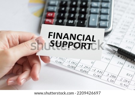 FINANCIAL SUPPORT text on a card in the hand of a businessman on the background of the table